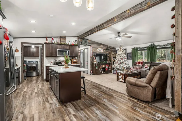 a large living room with stainless steel appliances granite countertop a couch and a large window with wooden floor