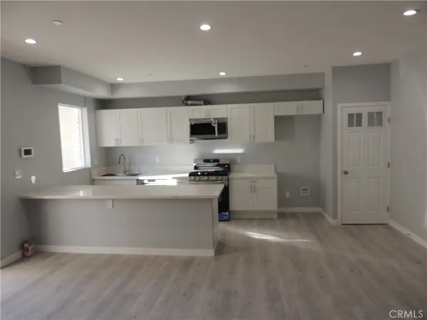 a kitchen with granite countertop a stove a sink and a refrigerator