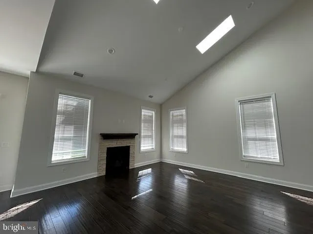 an empty room with wooden floor fireplace and windows