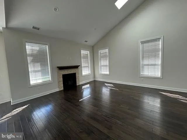 an empty room with wooden floor fireplace and windows
