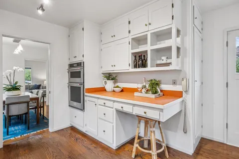 a kitchen with white cabinets and wooden floors