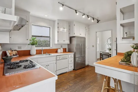 a kitchen with stainless steel appliances a dining table chairs refrigerator sink and stove