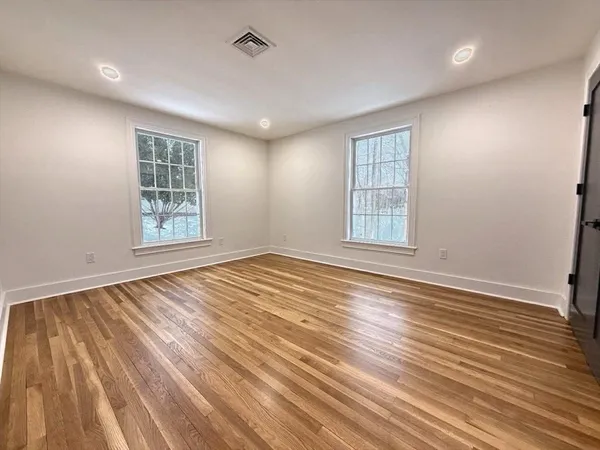 an empty room with wooden floor and windows