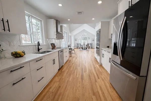 a open kitchen with stainless steel appliances granite countertop a refrigerator a sink dishwasher a stove and white countertops with wooden floor
