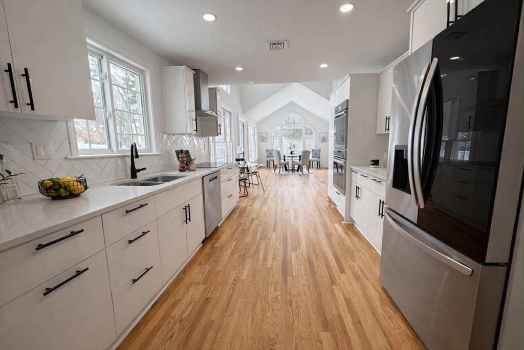 576 Grove Street Framingham, MA 01701 - Photo 5 of 38 a open kitchen with stainless steel appliances granite countertop a refrigerator a sink dishwasher a stove and white countertops with wooden floor