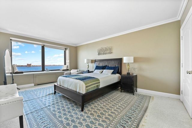 a bedroom with a large bed a couch and windows