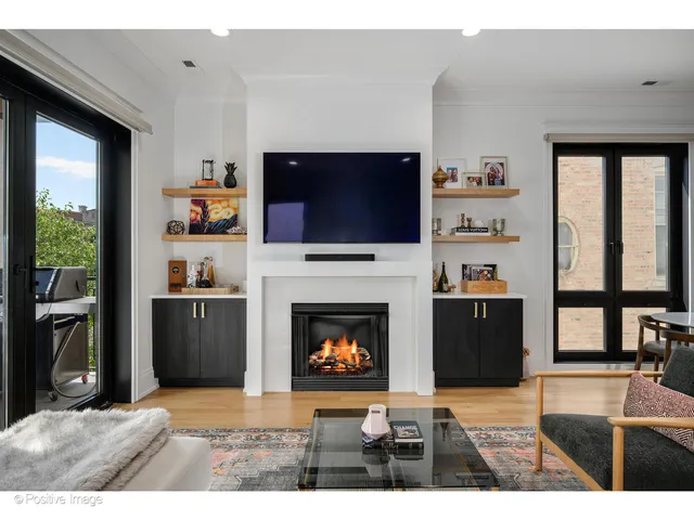 a living room with a fireplace a flat screen tv and a floor to ceiling window