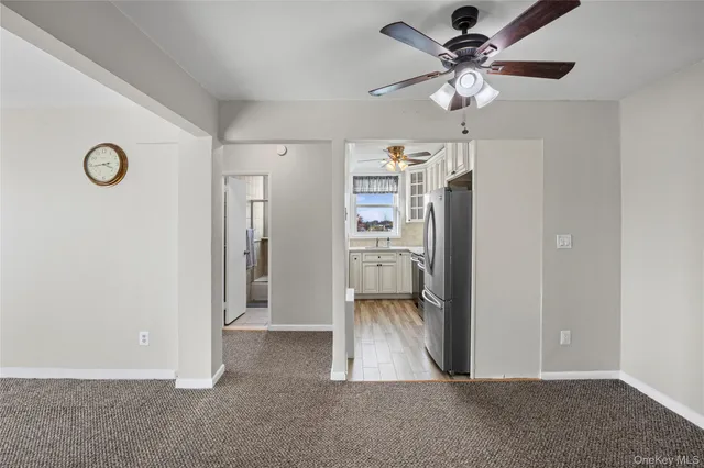 a view of a livingroom with a chandelier fan and a refrigerator