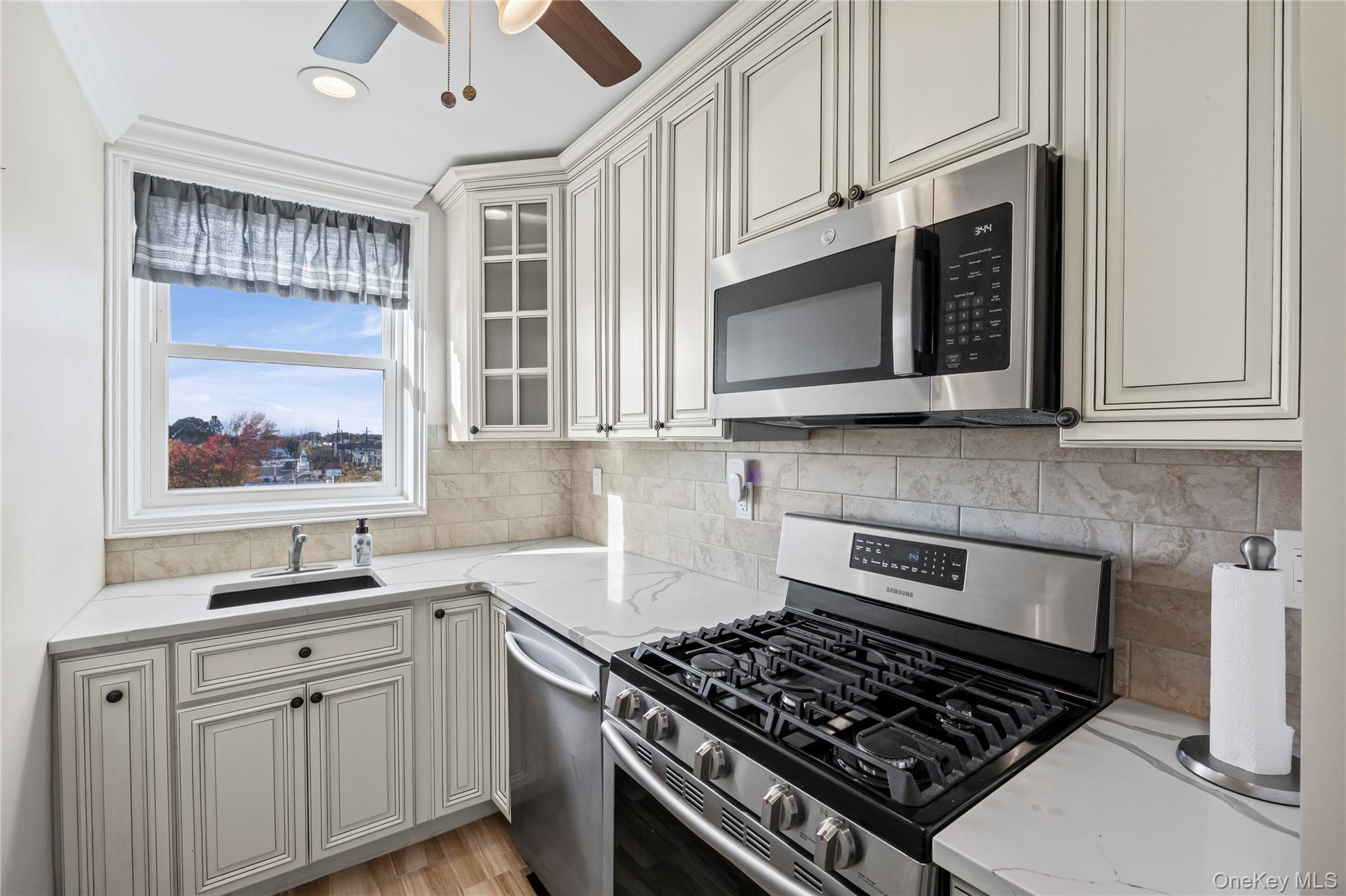 504 Merrick Road, Unit 4E Lynbrook, NY 11563 - Photo 5 of 19 a kitchen with stainless steel appliances granite countertop white cabinets a stove top oven and granite counter tops