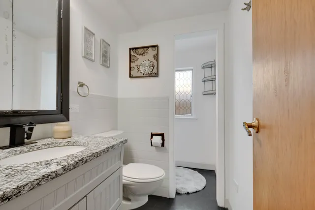 a bathroom with a granite countertop toilet sink and mirror