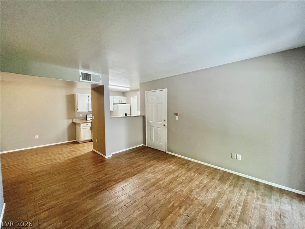 7885 West Flamingo Road, Unit 1029 Las Vegas, NV 89147 - Photo 4 of 18 Natural wood flooring complements this open concept living space, flowing into a well-appointed kitchen.
