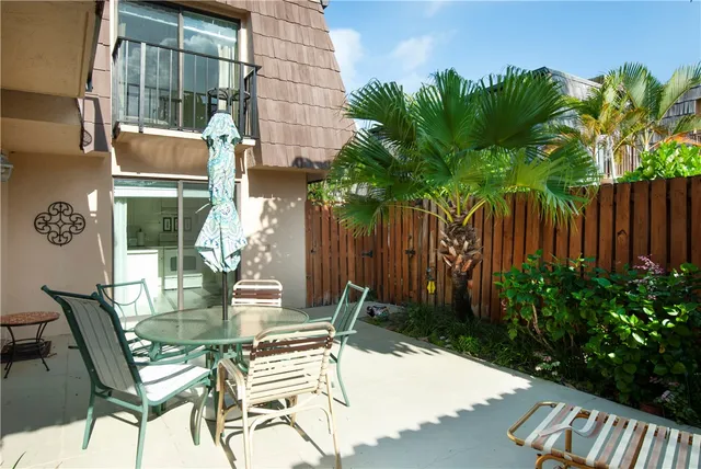 a view of a patio with table and chairs and potted plants with wooden fence