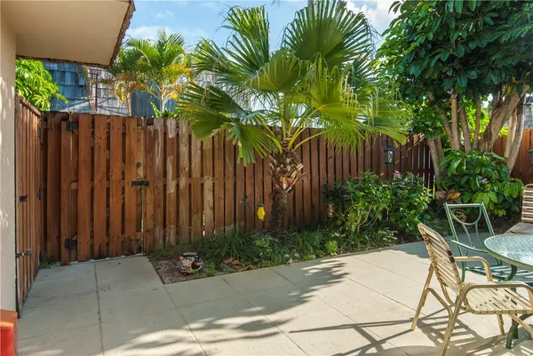 a backyard of a house with plants and trees with wooden fence