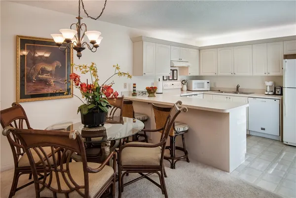 a dining room filled chandelier and kitchen view