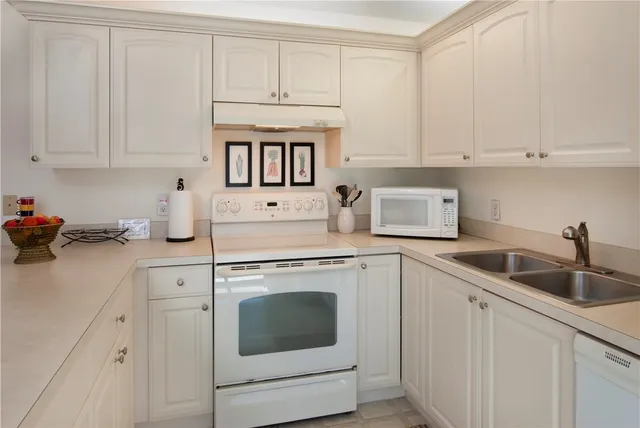 a kitchen with white cabinets and white appliances