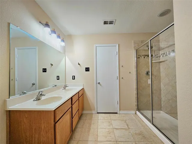 a bathroom with a double vanity sink mirror and shower