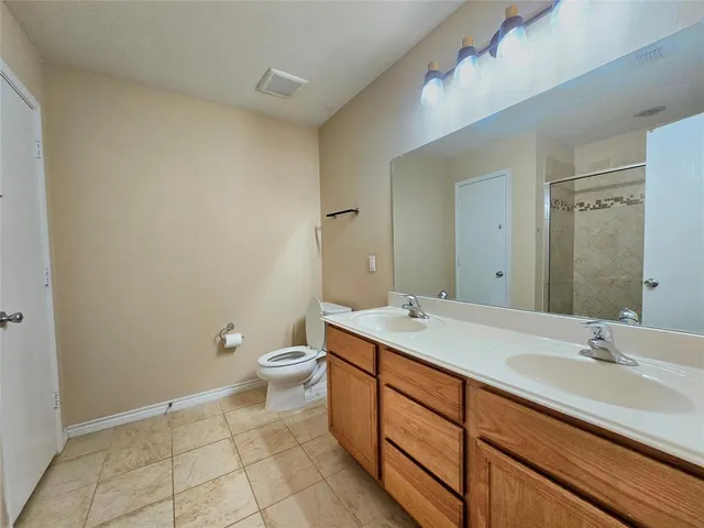 a spacious bathroom with a granite countertop sink a toilet and a mirror