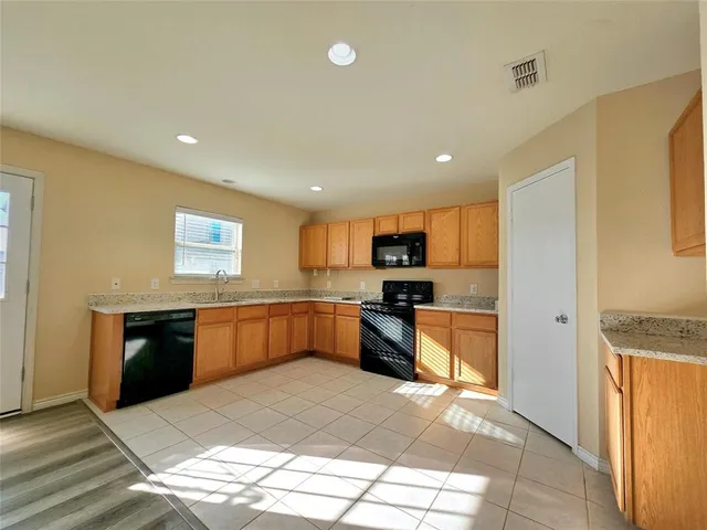 a large kitchen with stainless steel appliances kitchen island granite countertop a refrigerator and a stove top oven