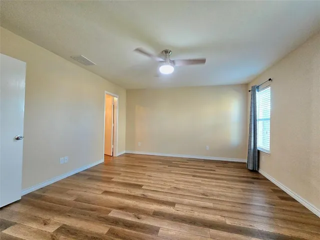 a view of empty room with wooden floor and fan