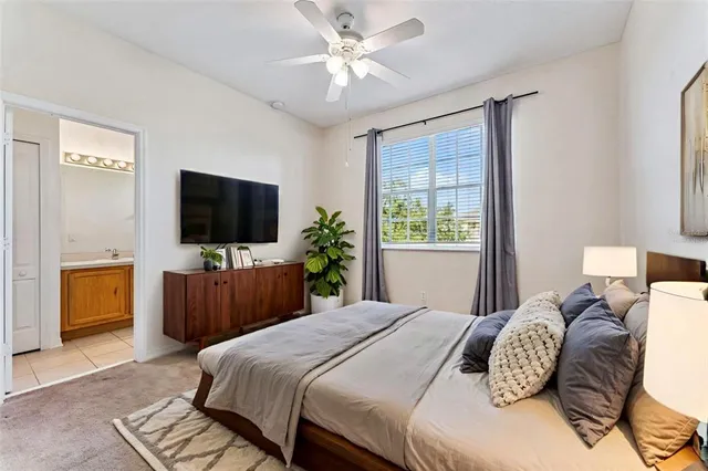 a bedroom with a bed television on desk and a window