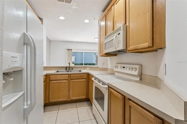 a kitchen with stainless steel appliances granite countertop a sink and dishwasher a refrigerator with wooden cabinets