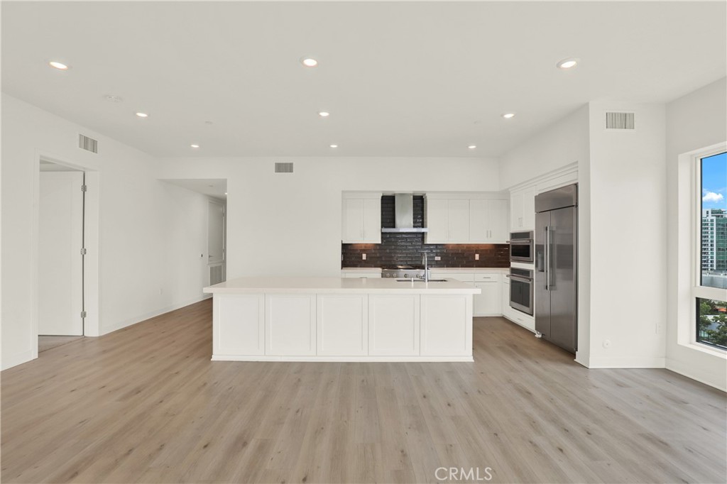 3715 Rivington Irvine, CA 92612 - Photo 8 of 65 a large white kitchen with kitchen island a sink a center island stainless steel appliances and a cabinets