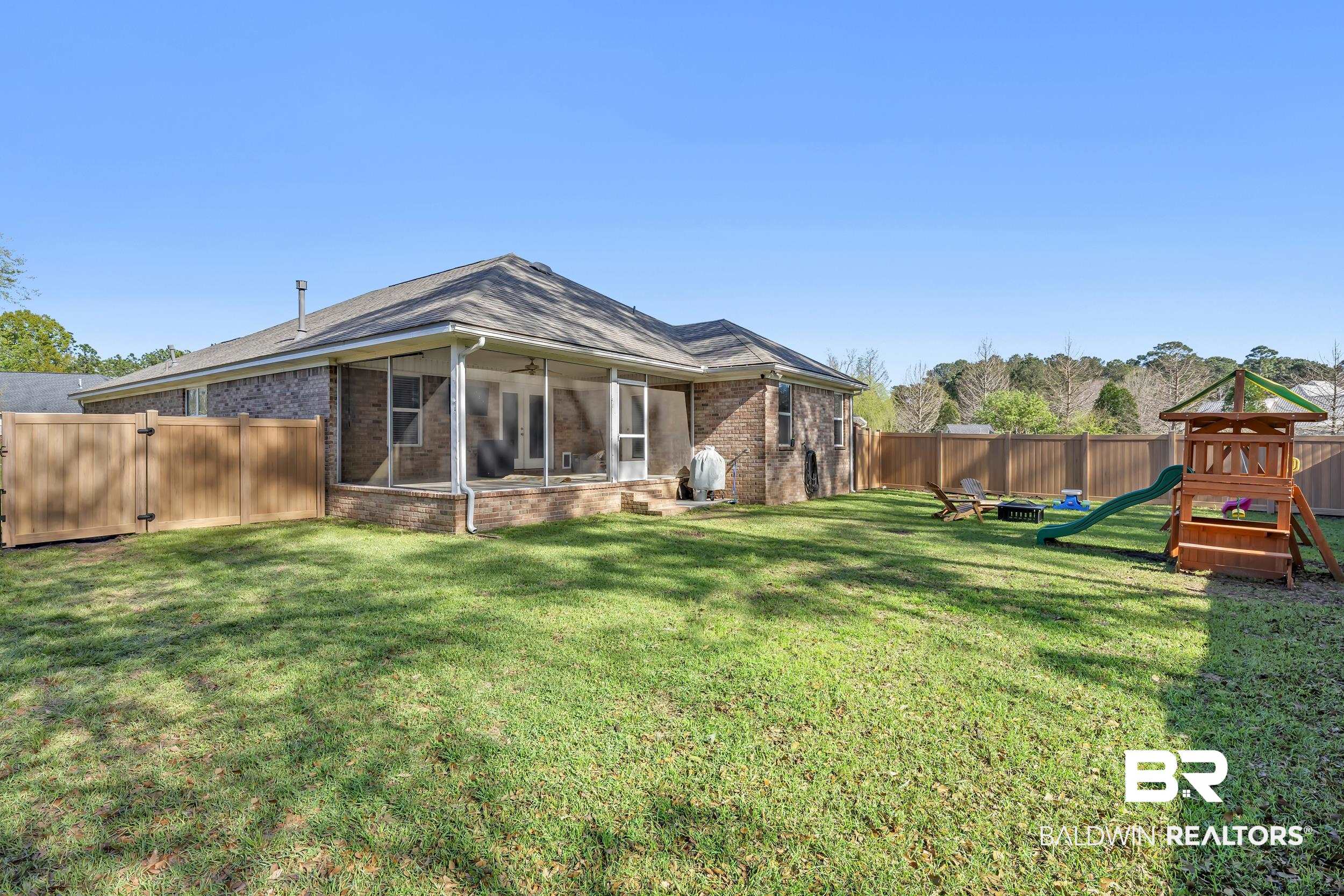 31527 Heidelbrook Loop Daphne, AL 36527 - Photo 2 of 22 Rear view of house with a sunroom, a fenced backyard, brick siding, a playground, and a gate