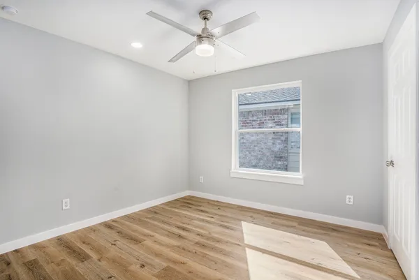 an empty room with a window and a ceiling fan