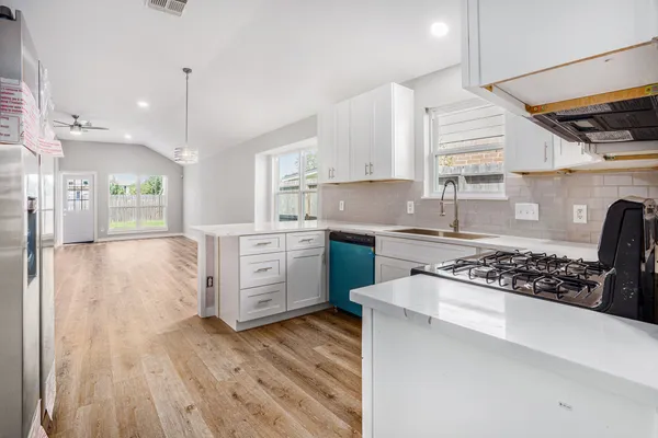 a kitchen with stainless steel appliances granite countertop a stove a sink dishwasher and a refrigerator with wooden floor