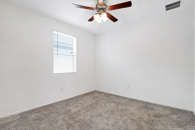 an empty room with windows and fan