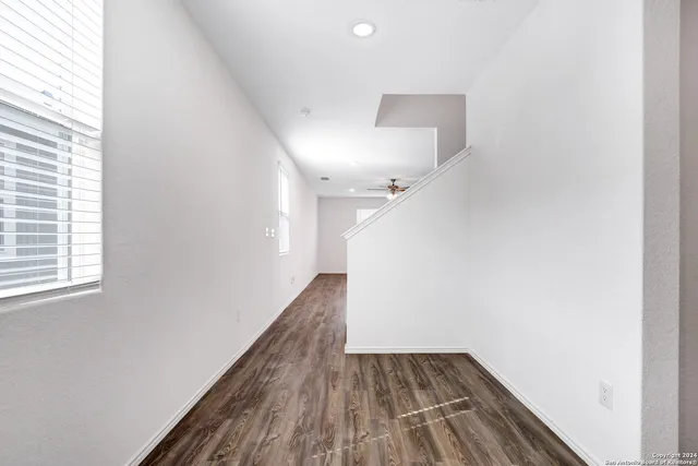 a view of a hallway with wooden floor and a window