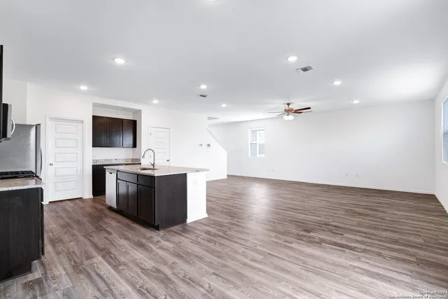 a view of kitchen with stainless steel appliances kitchen island hard wood floors and fireplace