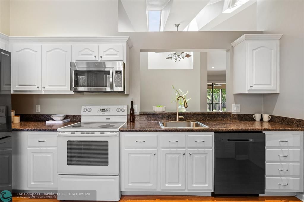 9804 Northwest 1st Court, Unit 9804 Plantation, FL 33324 - Photo 6 of 25 a kitchen with stainless steel appliances granite countertop a stove a microwave oven a sink dishwasher and cabinets with wooden floor