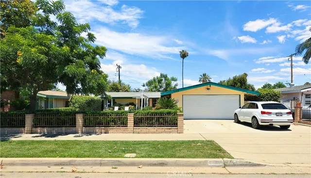a front view of a house with a garden and tree