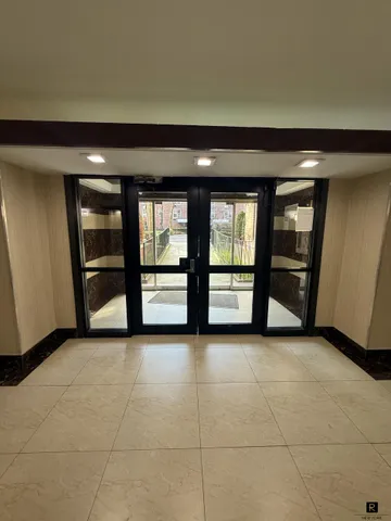 a view of an empty room with a window and a kitchen