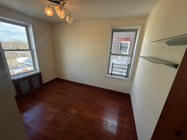 a view of an empty room with wooden floor and windows