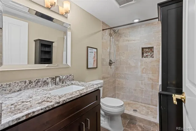 a bathroom with a granite countertop sink toilet and shower