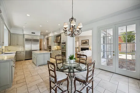a dining room filled a chandelier and kitchen view