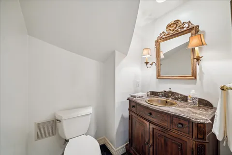 a bathroom with a granite countertop toilet sink and mirror