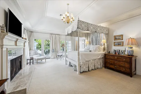 a spacious bedroom with a bed fireplace and flat screen tv