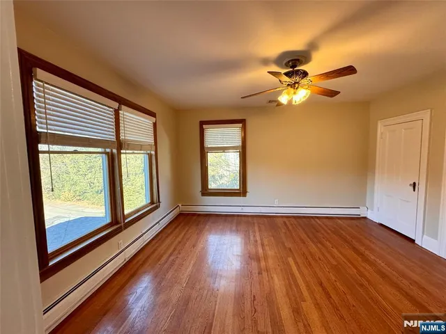 a view of empty room with wooden floor and fan