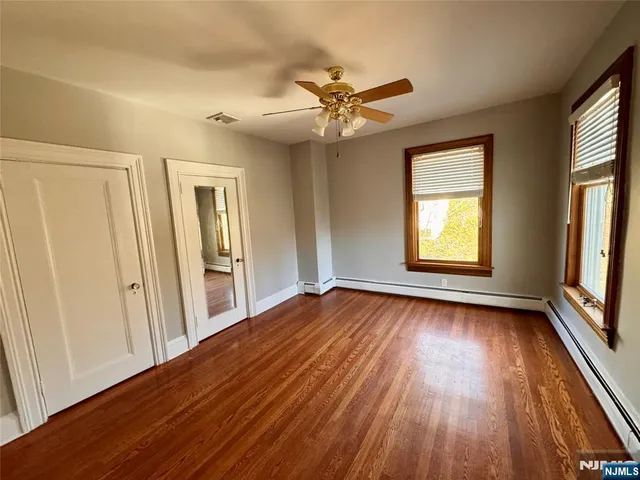 an empty room with wooden floor fan and windows