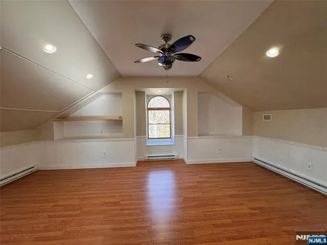 an empty room with wooden floor fan and windows