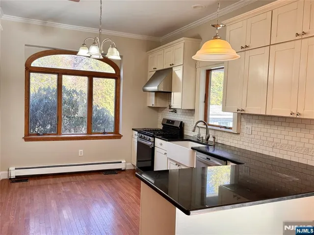 a kitchen with stainless steel appliances granite countertop a sink a stove and a wooden floors