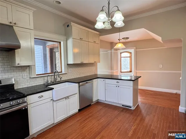 a kitchen with stainless steel appliances granite countertop wooden floors a stove a sink and a microwave