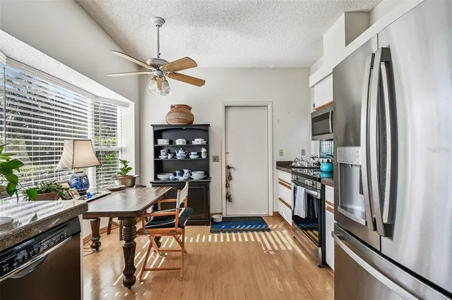 a kitchen with stainless steel appliances a stove a refrigerator and a dining table with wooden floor