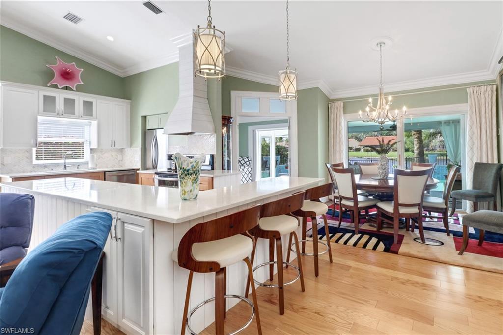 310 Fox Den Circle Naples, FL 34104 - Photo 12 of 46 a dining room with stainless steel appliances kitchen island granite countertop a table chairs and a chandelier