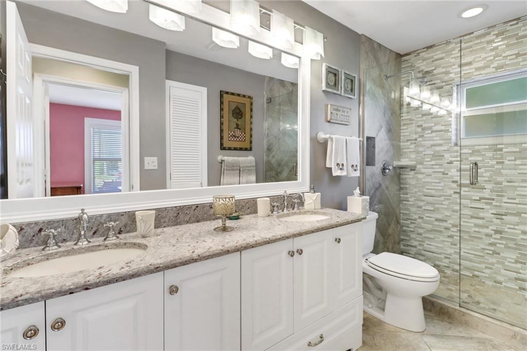 310 Fox Den Circle Naples, FL 34104 - Photo 21 of 46 a bathroom with a granite countertop toilet a sink and a mirror