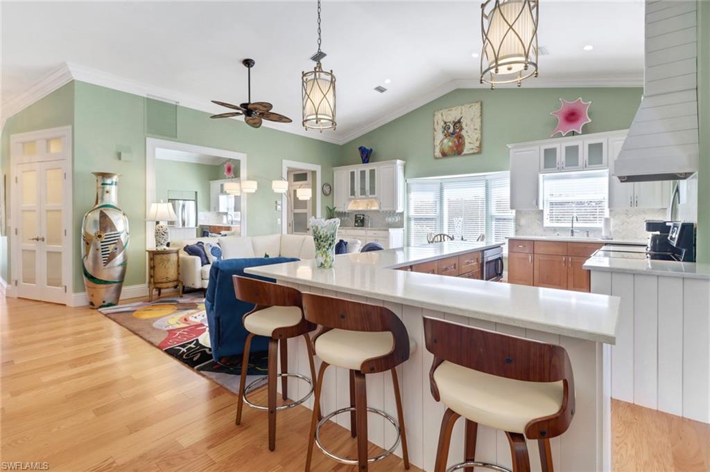 310 Fox Den Circle Naples, FL 34104 - Photo 4 of 46 a very nice looking open dining room with kitchen island wooden floor and a chandelier