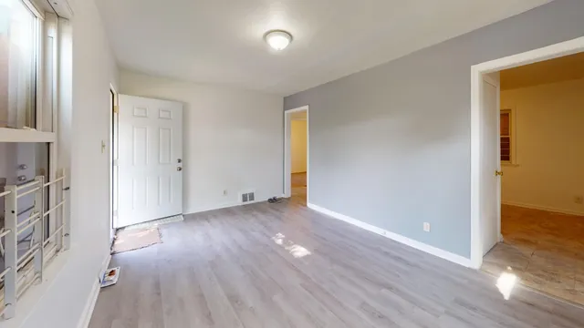 an empty room with wooden floor and windows